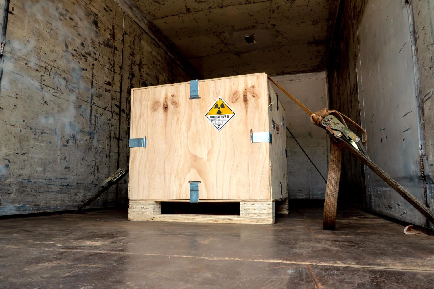 Wooden crate with radioactive symbol secured inside a truck.