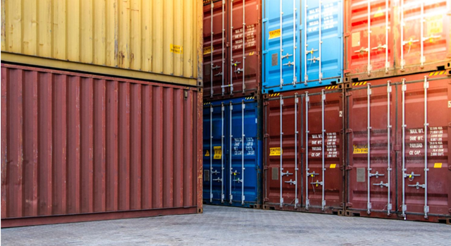 Stacked shipping containers in various colors at a port.