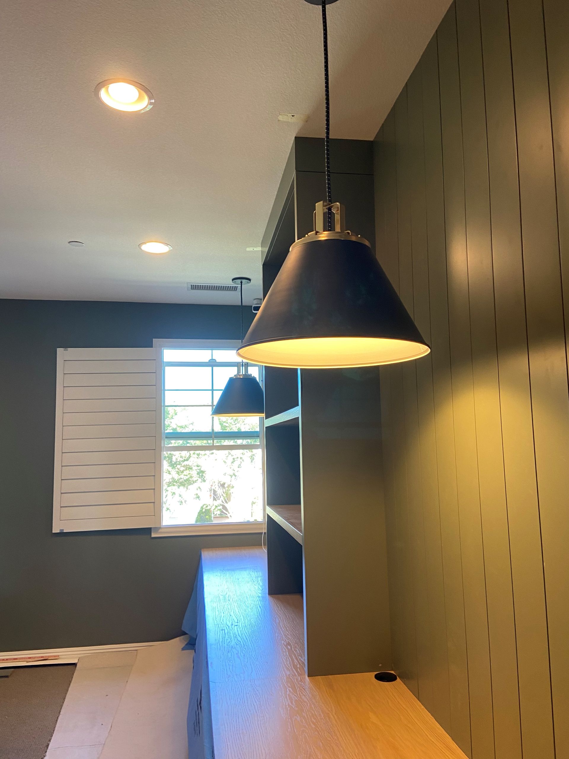 A room with a window and a lamp hanging from the ceiling