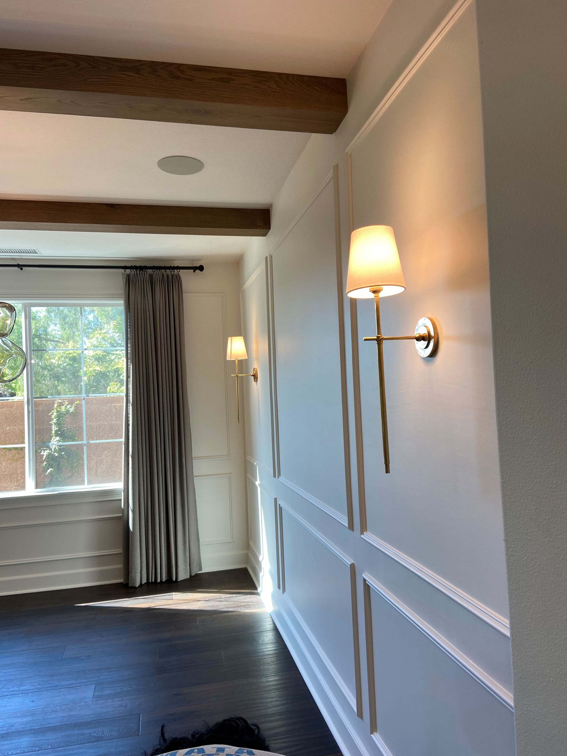 A living room with white walls and a lamp on the wall