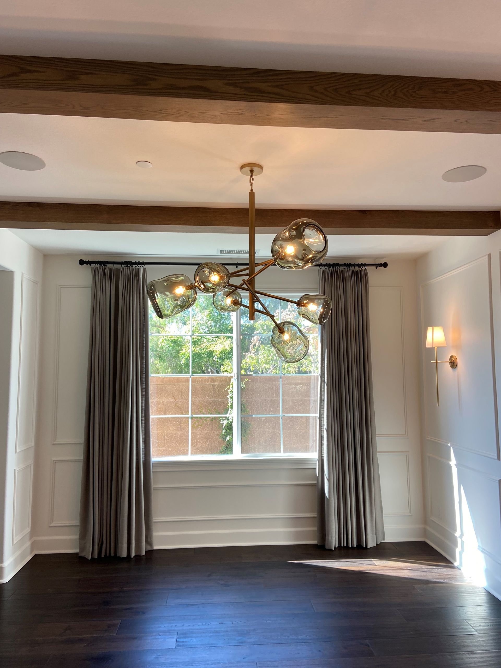 An empty room with a chandelier hanging from the ceiling and a window.