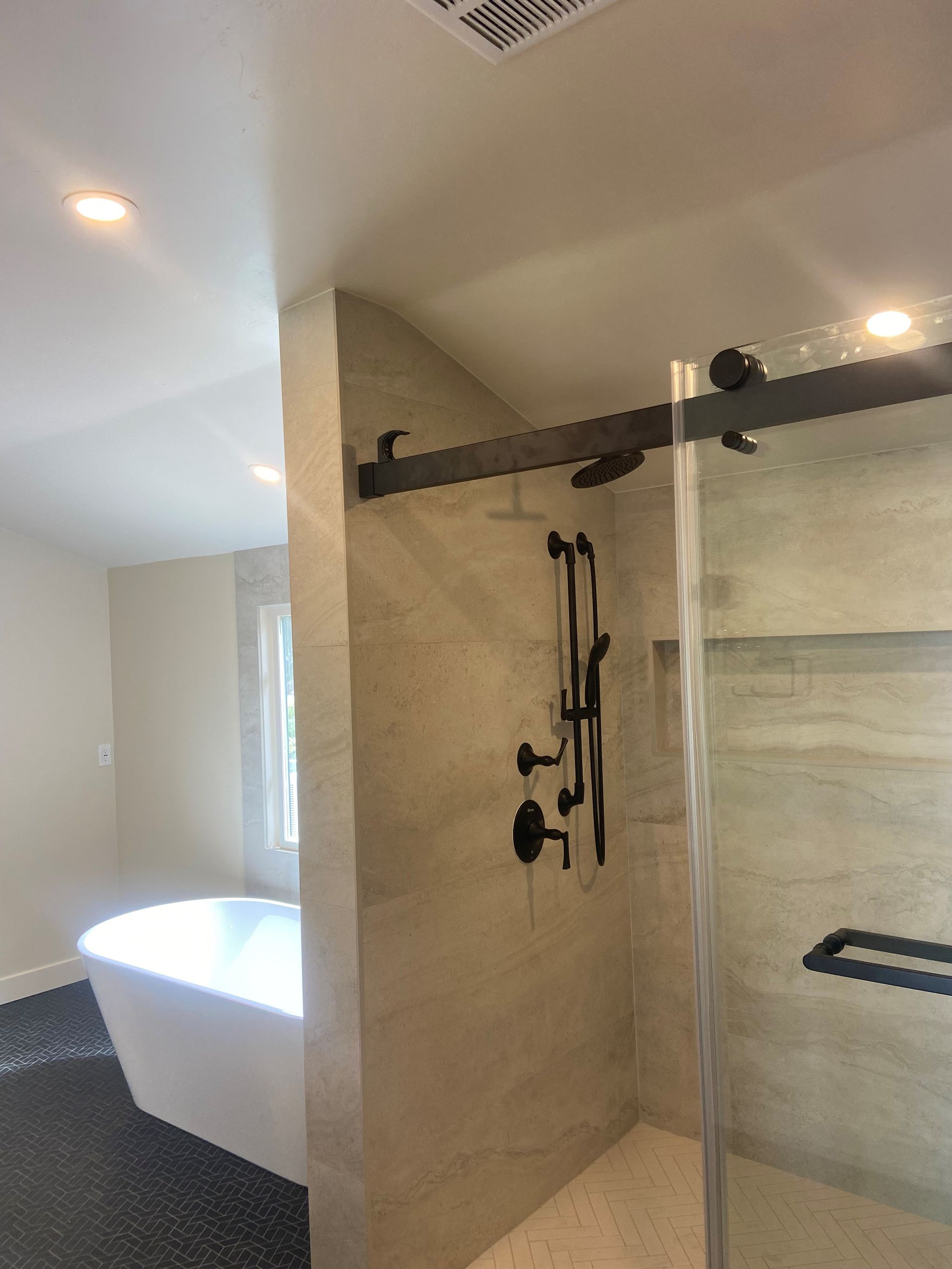 A bathroom with a tub , shower , and sliding glass door.