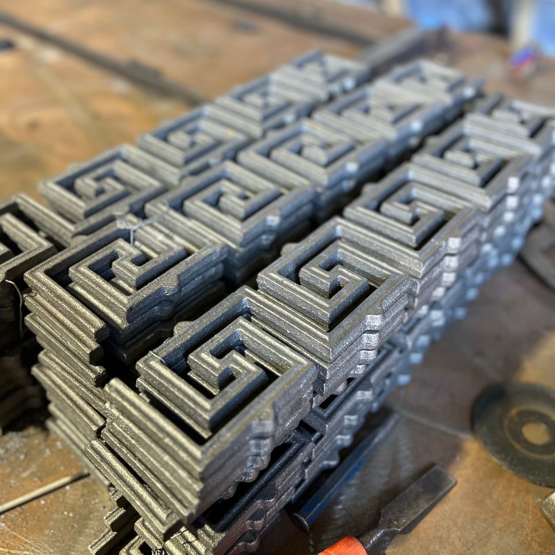 A stack of metal pieces with a greek key pattern on them.