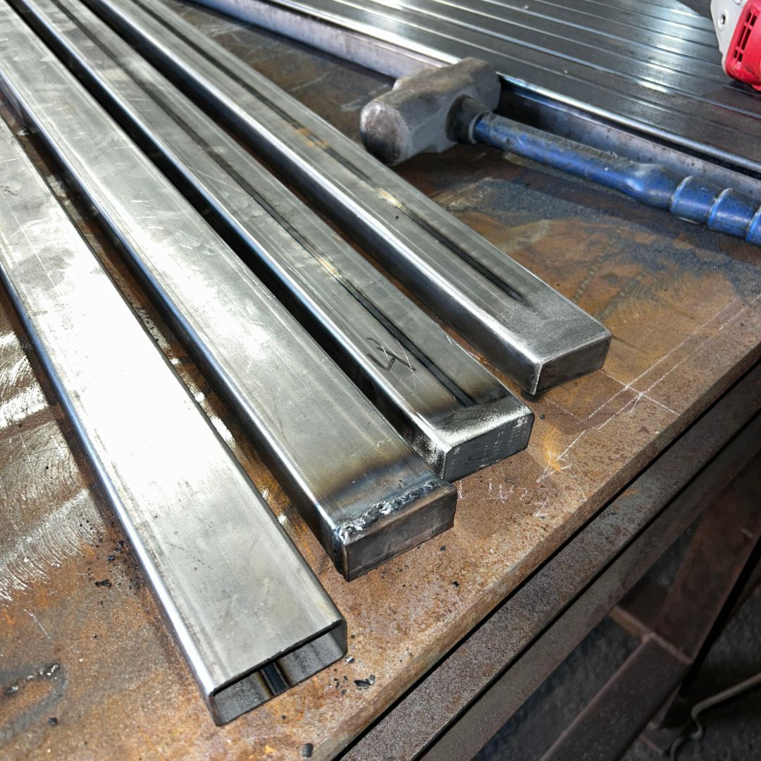 A hammer is sitting on a table next to a bunch of metal bars