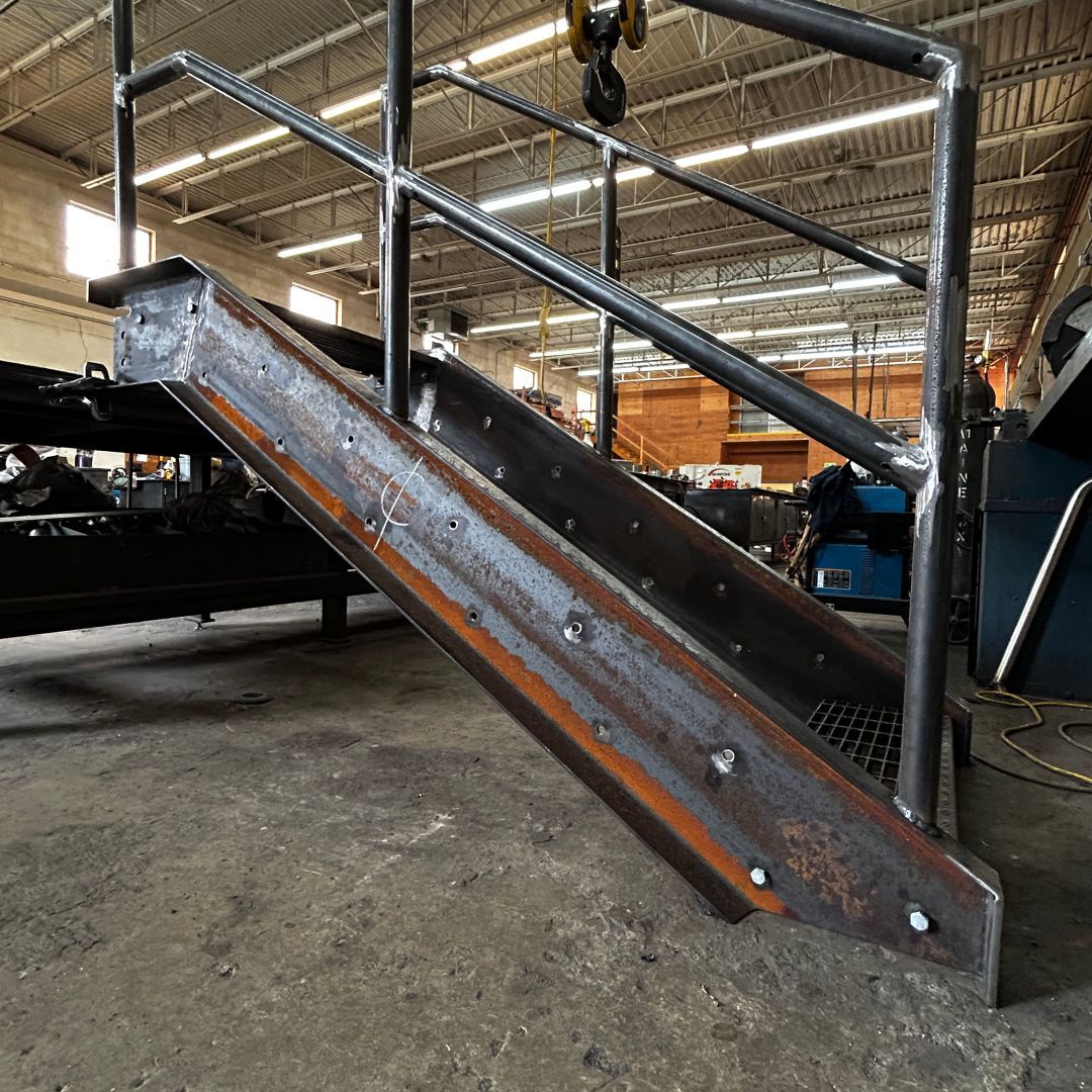 A metal staircase is being built in a factory
