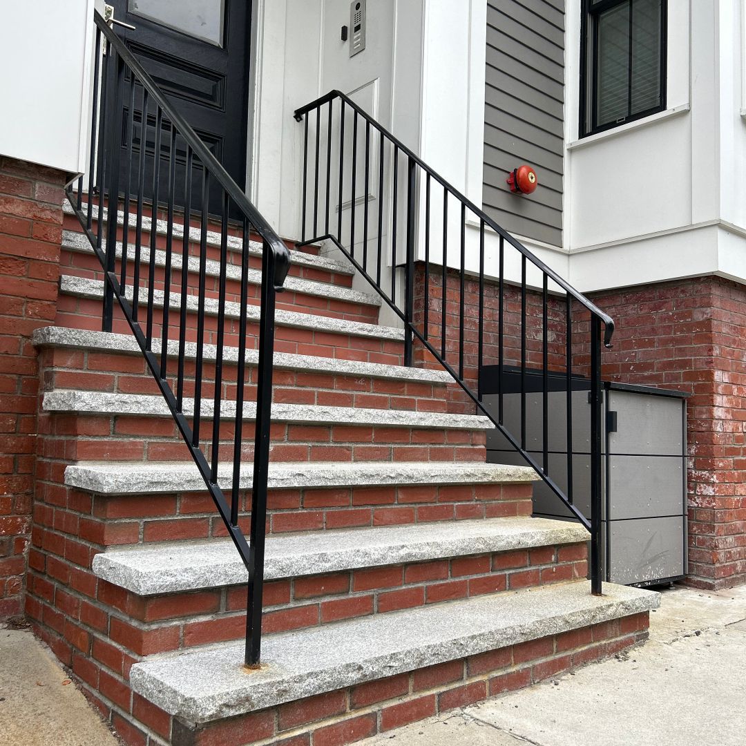 A set of stairs leading up to a house with a black railing