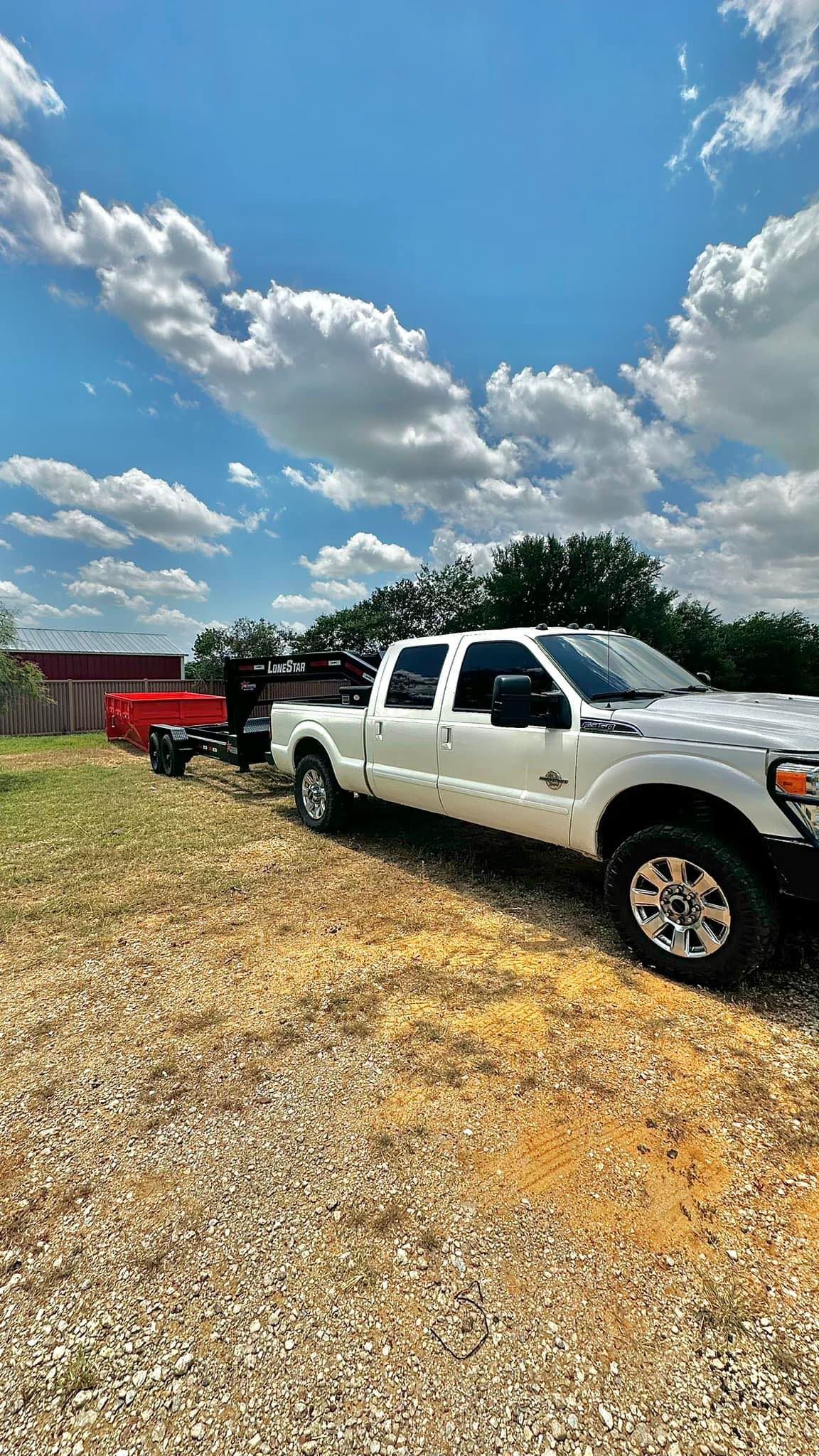 A white truck is parked in a gravel lot.