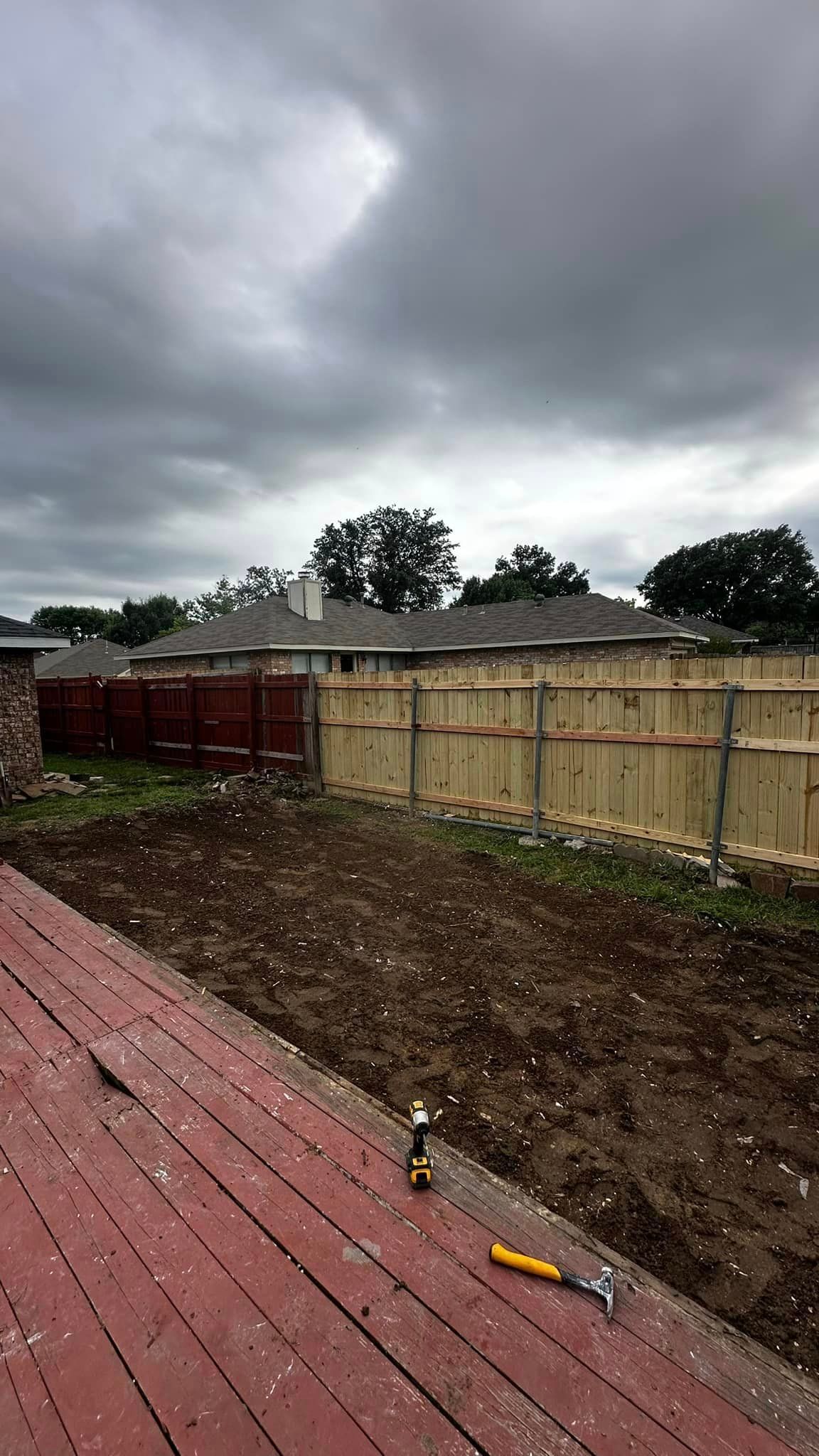 A roof with hail on it and a fence in the background.