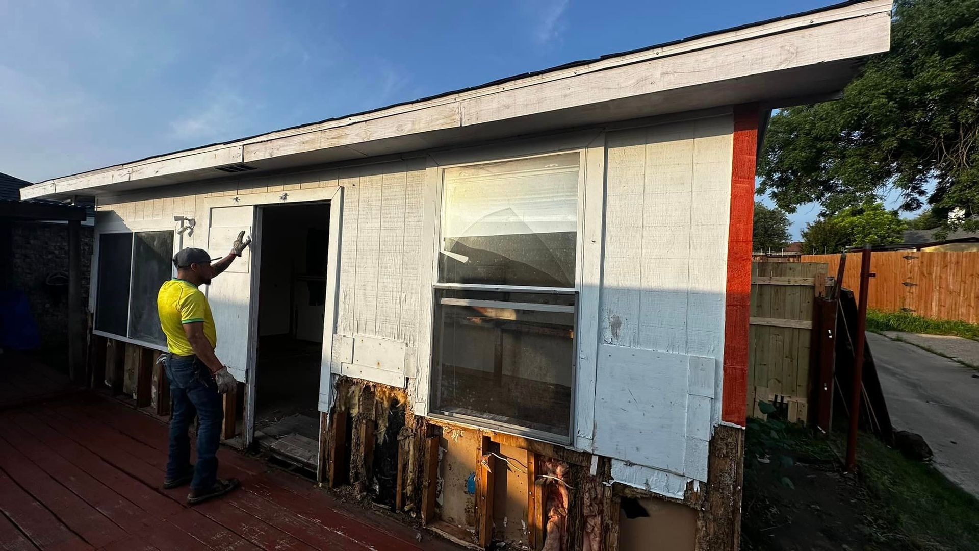 A man is standing in front of a small white house.