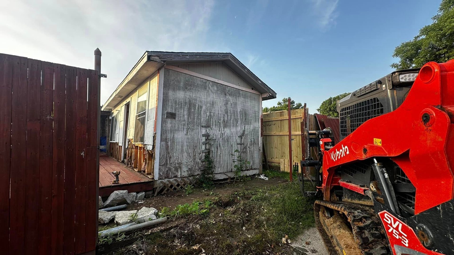 A red bulldozer is parked in front of a small house.