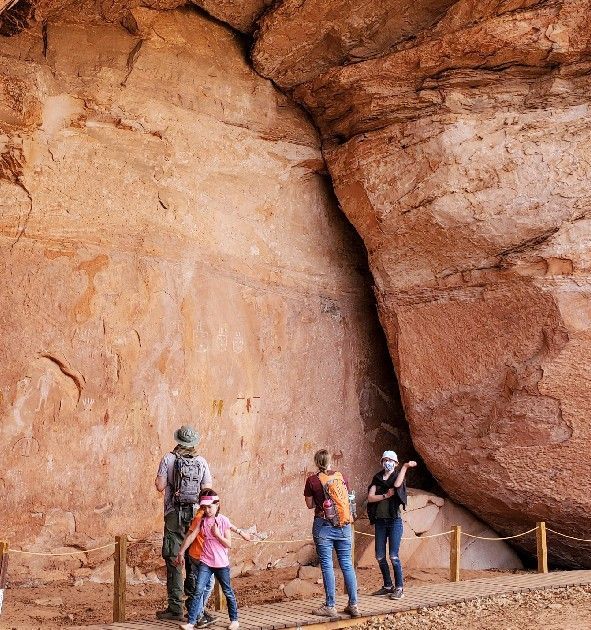 A group of people standing in front of a large rock wall