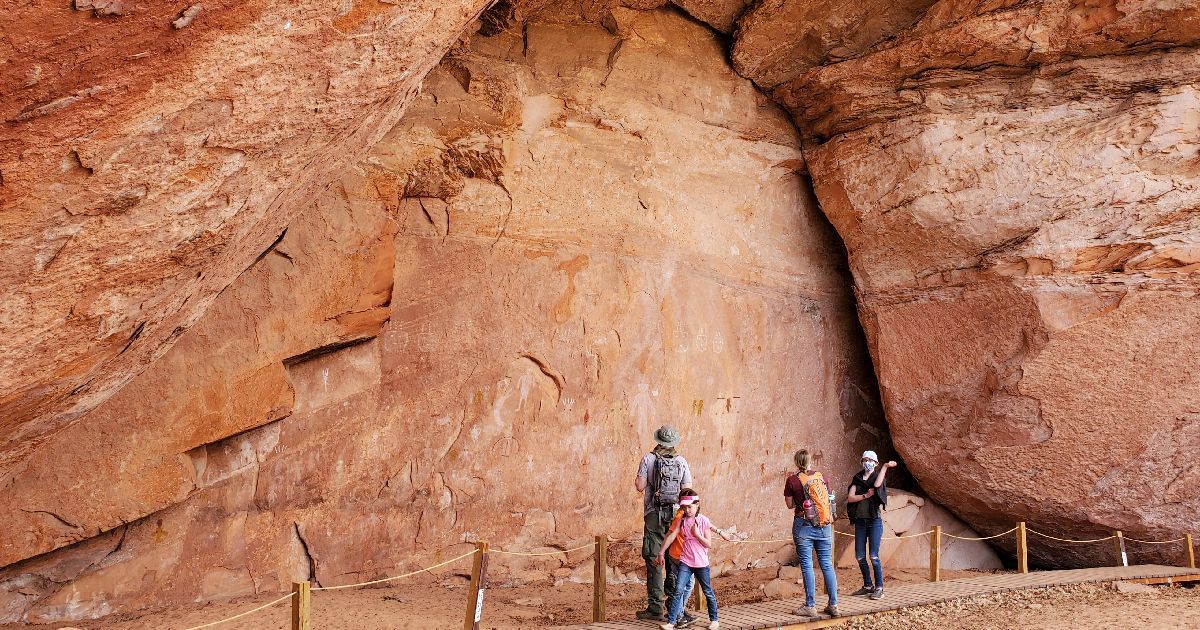 A group of people standing in front of a large rock