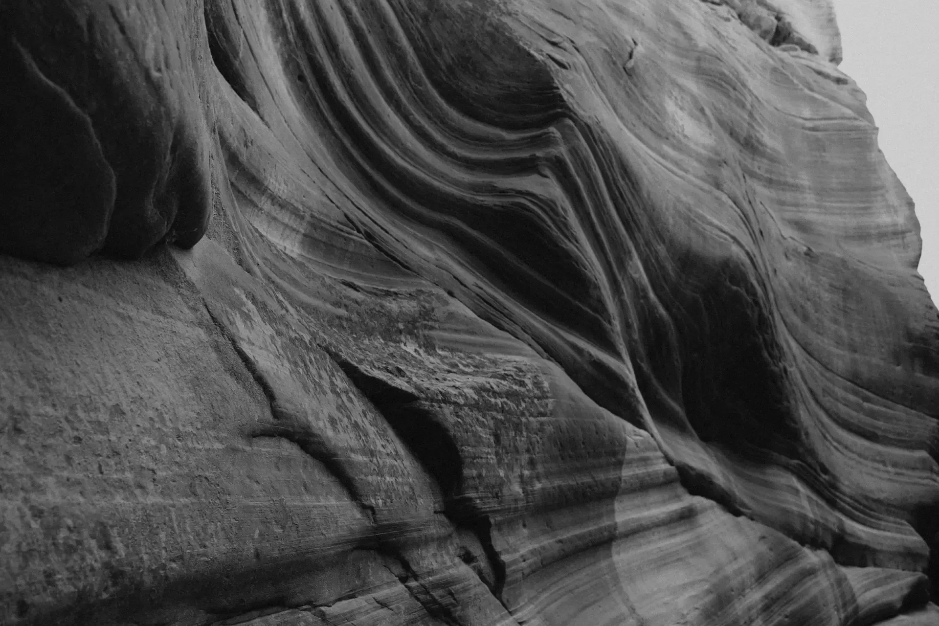 Black-and-white close-up of layered sandstone rock formations with sweeping curved textures