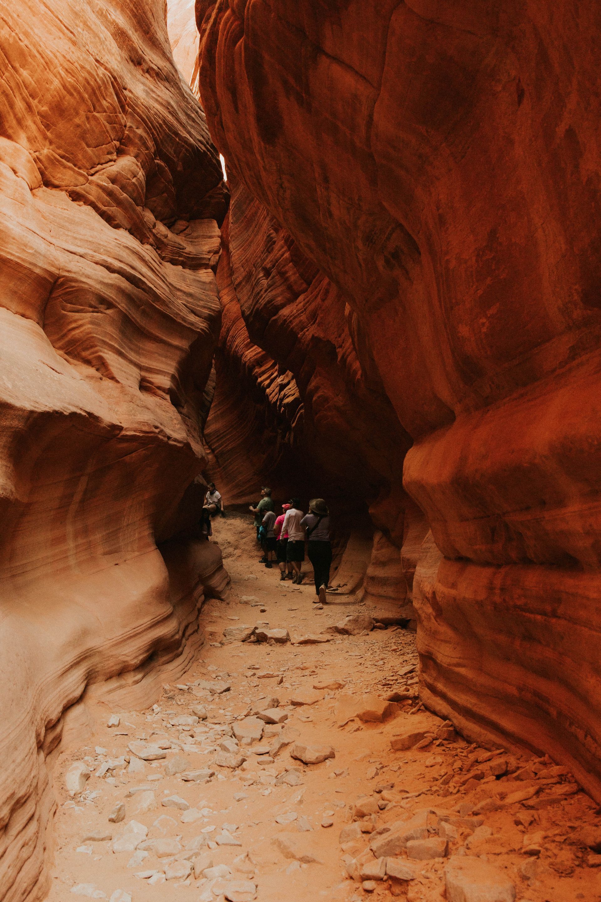A group of people are walking through a canyon.