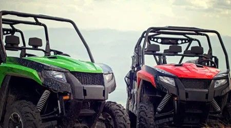 Two atvs are parked next to each other on top of a hill.