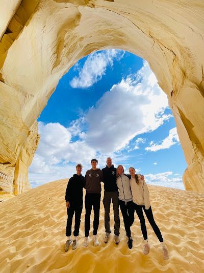 A group of people are posing for a picture under an archway in the desert.