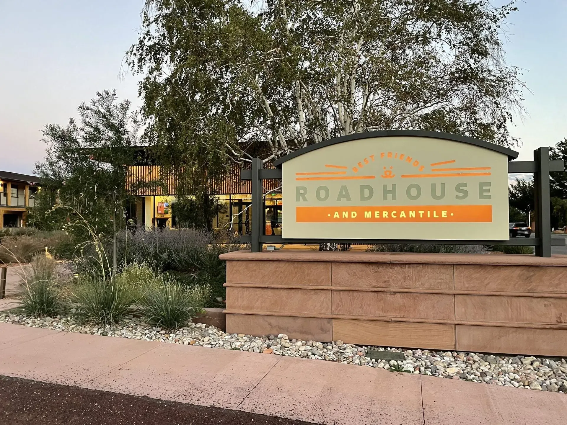 Roadhouse restaurant sign in a desert landscape with trees and stone landscaping