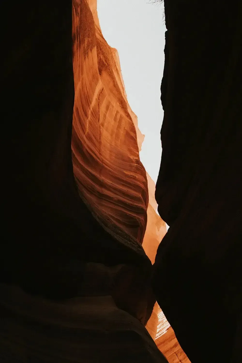 Narrow red sandstone canyon walls framing a bright sliver of sky