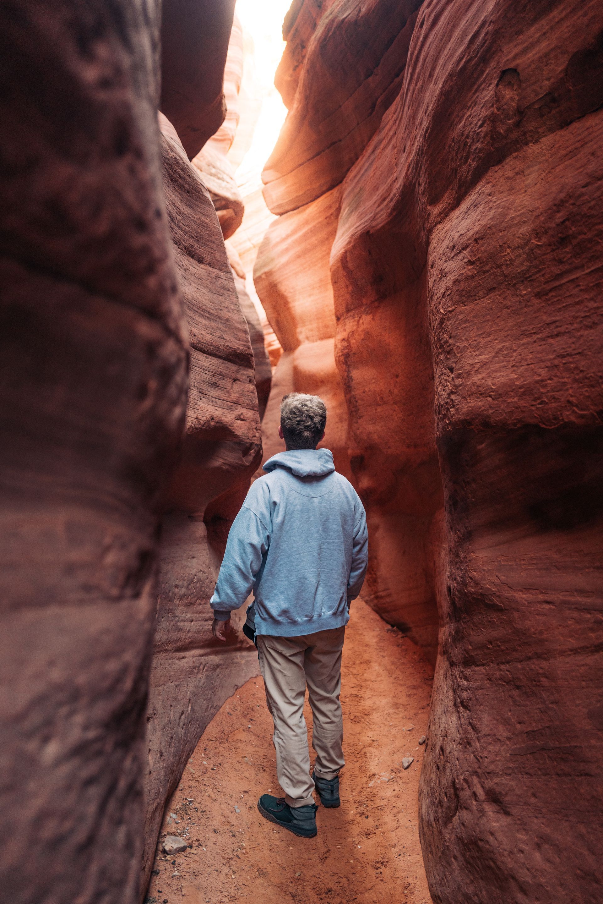 A man is walking through a canyon in the desert.