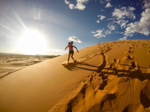 A woman is sitting on top of a atv in the desert at sunset.