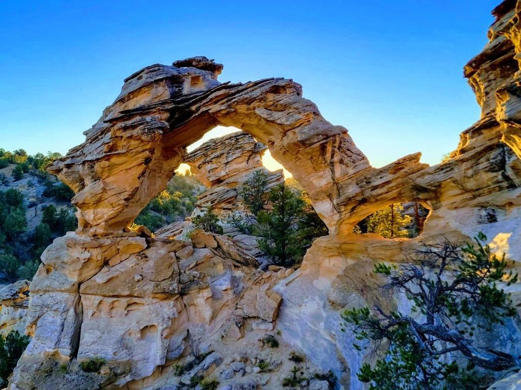A large rock formation in the middle of a canyon with a blue sky in the background.