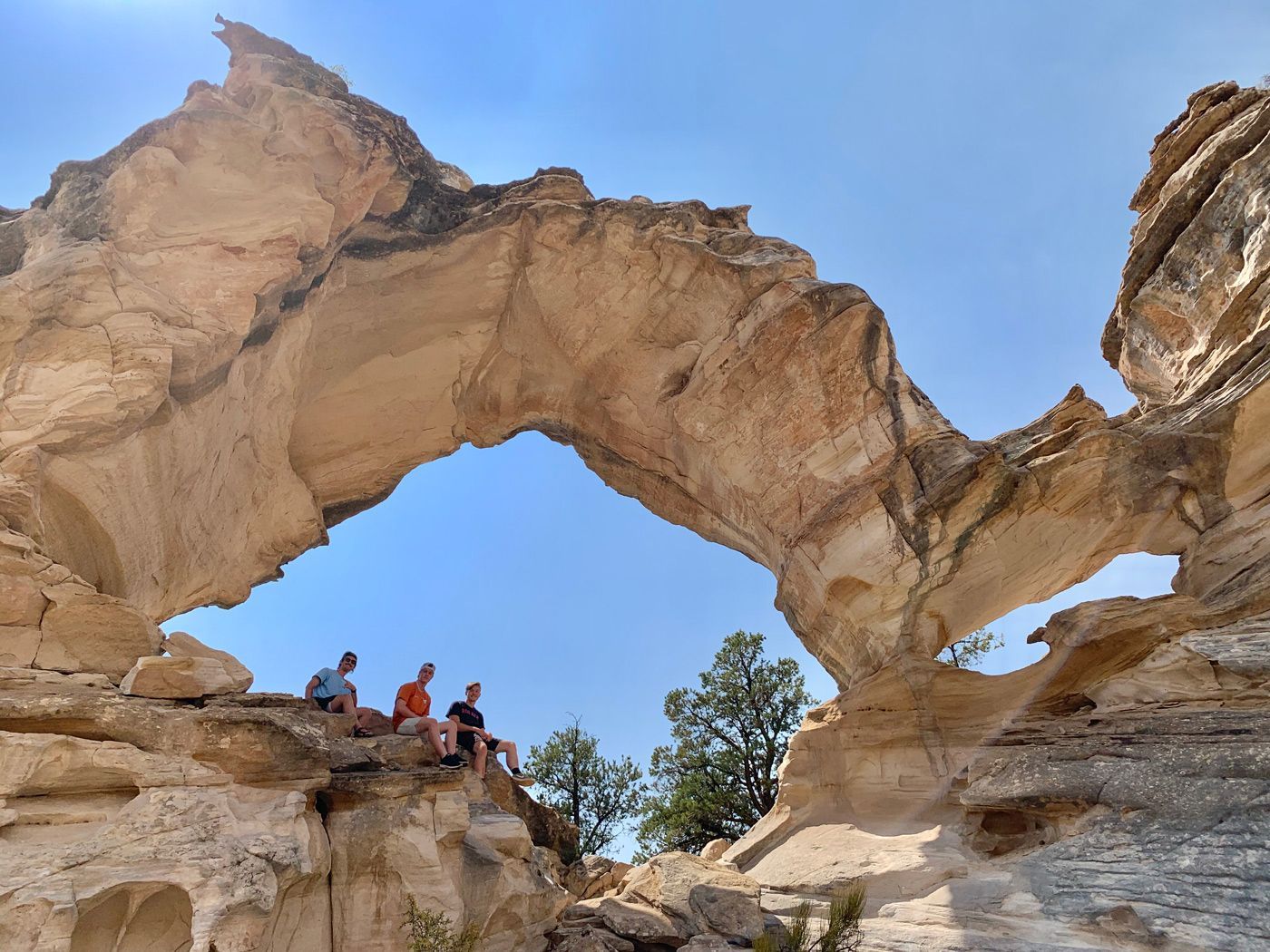 A group of people are standing under a large rock arch.
