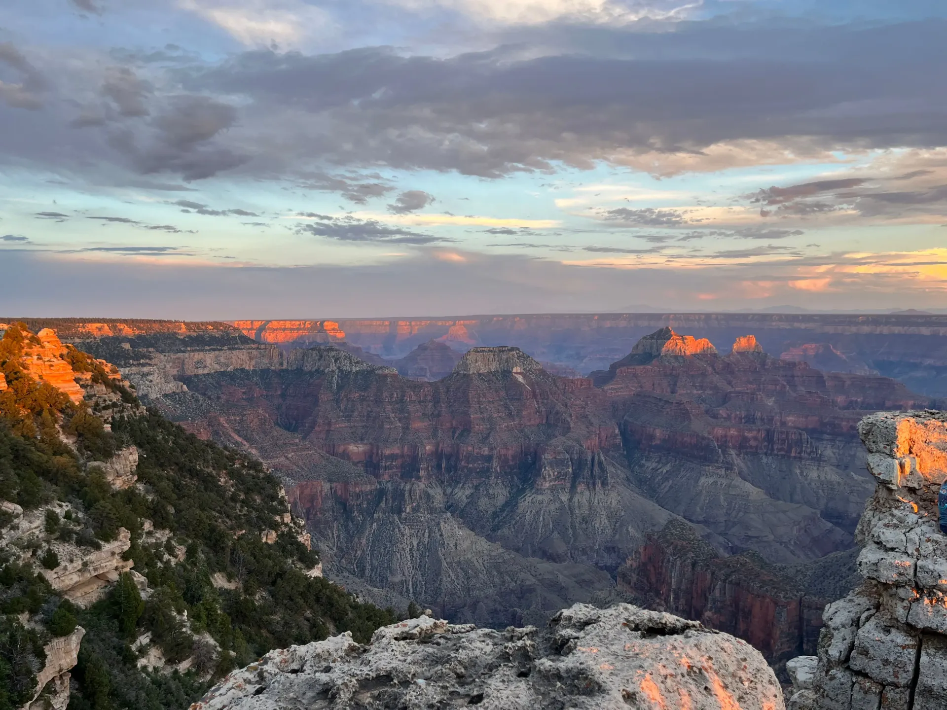 Sunset over the Grand Canyon, with layered cliffs and warm light on the rocky rim