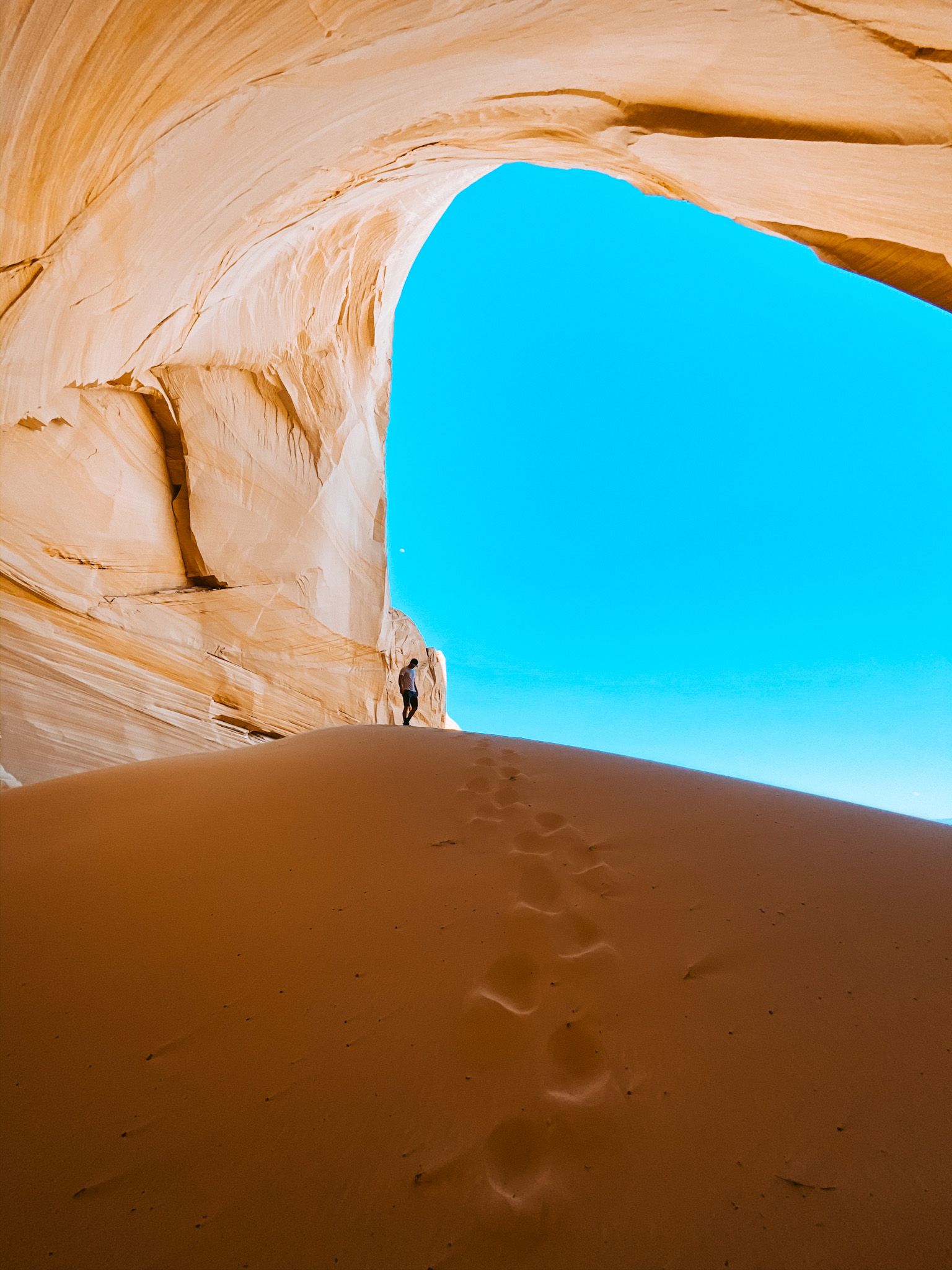 A person standing in a cave with a blue sky behind them
