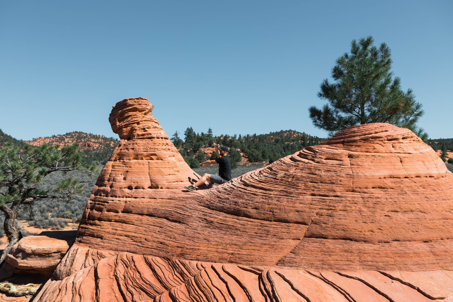 A person sits on top of a rock formation in the desert