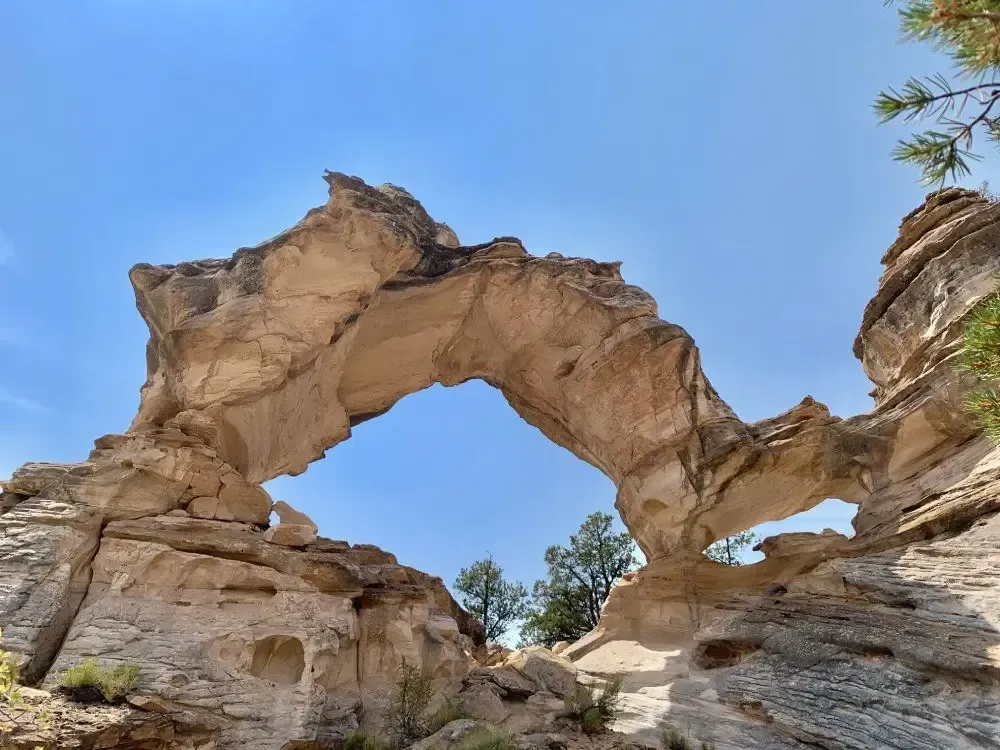A large rock formation in the middle of a canyon with a blue sky in the background.