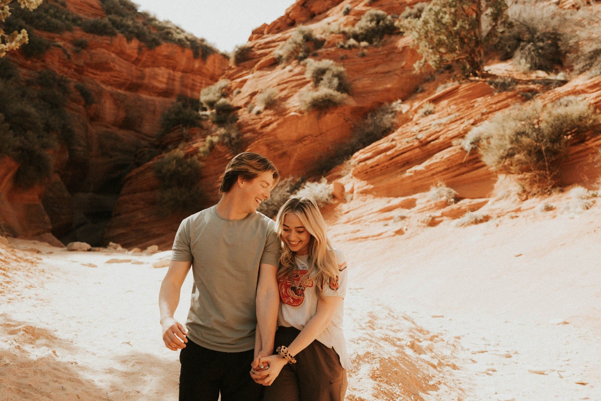 A man and a woman are holding hands in front of a mountain.