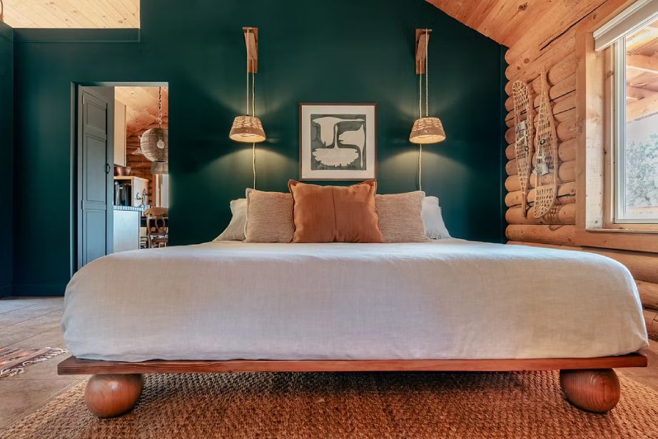A bedroom in a log cabin with a king size bed and green walls.