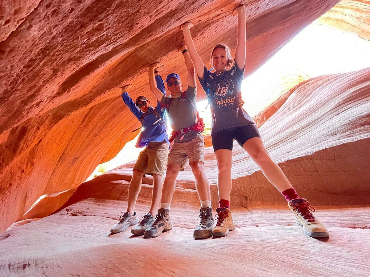 A group of people are standing in a cave with their arms in the air.