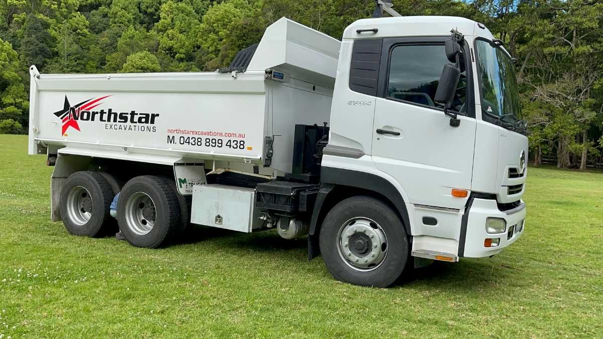 A White Dump Truck Is Parked In A Grassy Field — Northstar Excavations In Alstonville, NSW