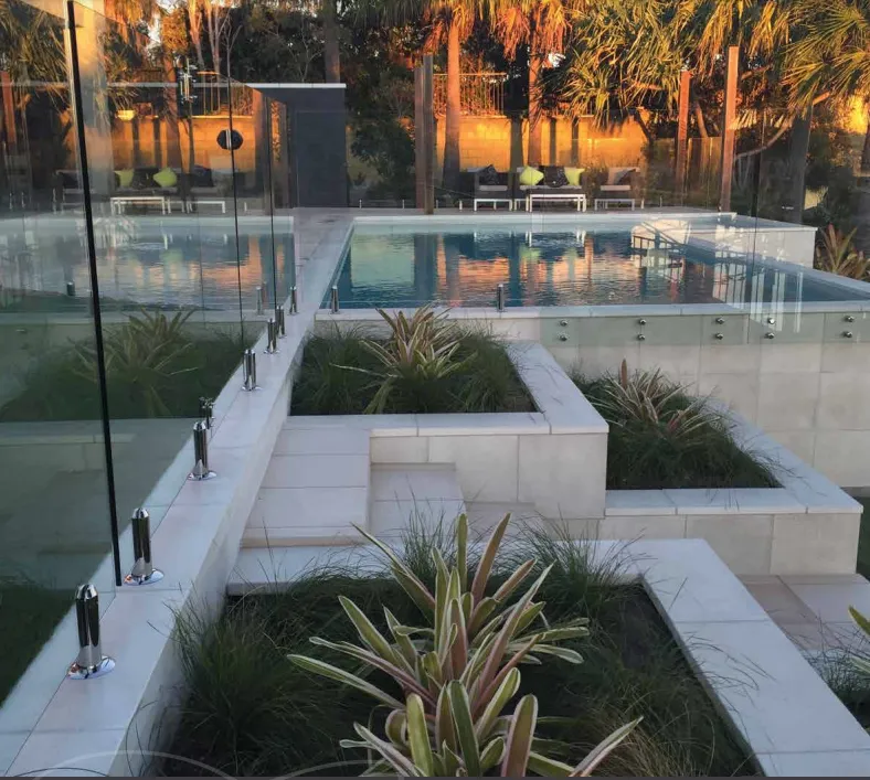 Luxurious Pool Area With Tiered Garden Beds and Palm Trees at Sunset — Hunter Valley Bricks & Pavers in Scone, NSW