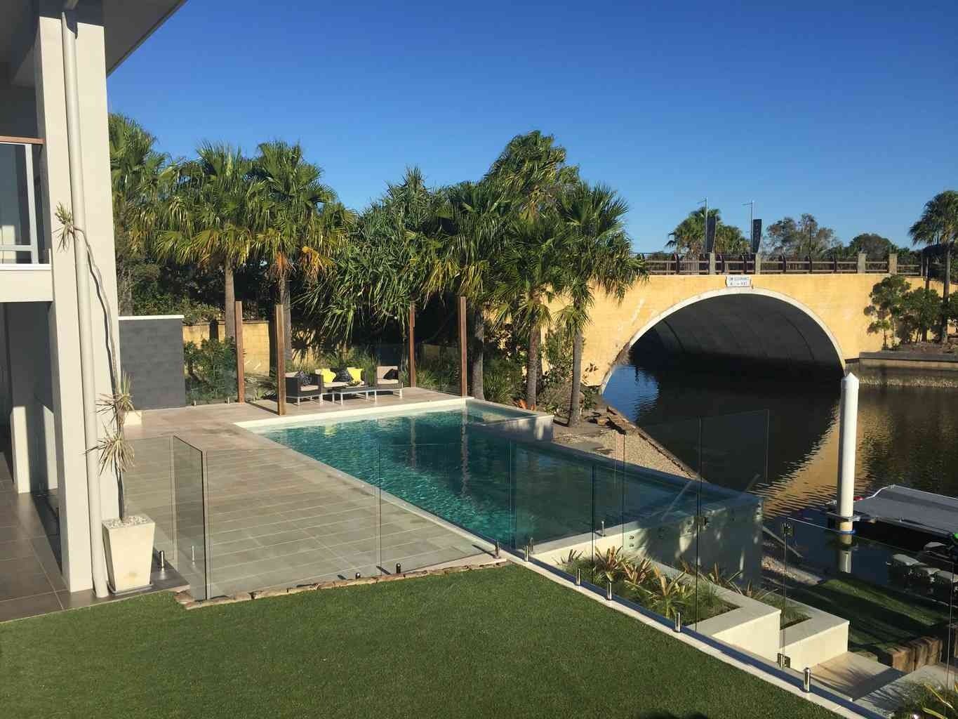 Poolside View of House, Pool, Palm Trees, and Arched Bridge Reflected in Water — Hunter Valley Bricks & Pavers in Scone, NSW