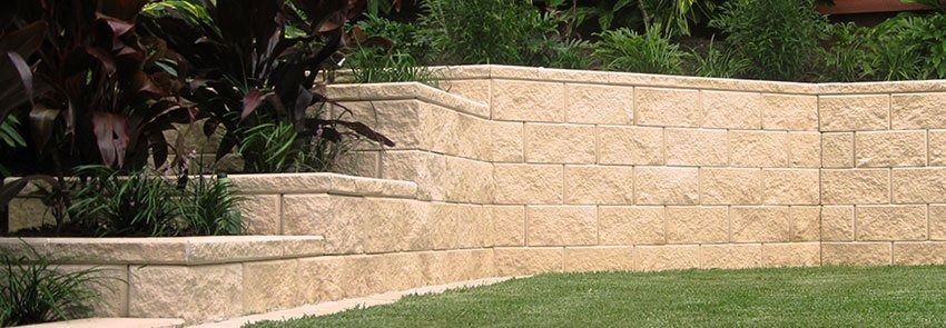 Stone Retaining Wall With Plants and Grass — Hunter Valley Bricks & Pavers in Scone, NSW