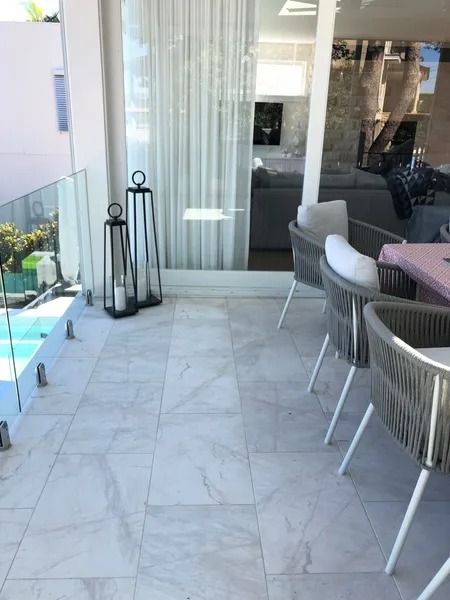 Outdoor Patio With Marble-like Tiles, Glass Railing, and Modern Furniture — Hunter Valley Bricks & Pavers in Scone, NSW