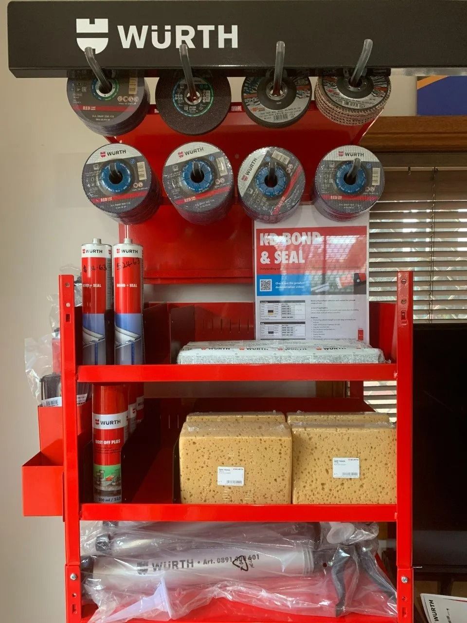Red Würth Display Rack With Grinding Discs, Sealant, and Sponges, in a Room — Hunter Valley Bricks & Pavers in Scone, NSW