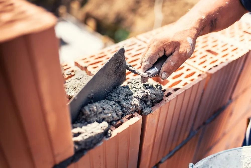 Bricklayer Using a Trowel to Apply Mortar on a Course of Red Bricks — Hunter Valley Bricks & Pavers in Scone, NSW