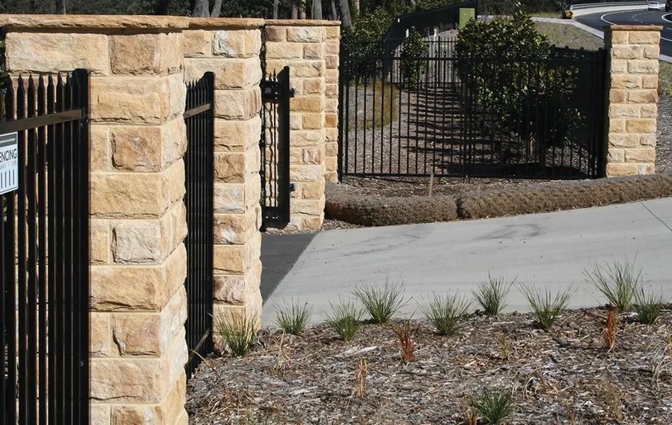 Stone Pillars With Black Metal Fence at Driveway Entrance — Hunter Valley Bricks & Pavers in Scone, NSW