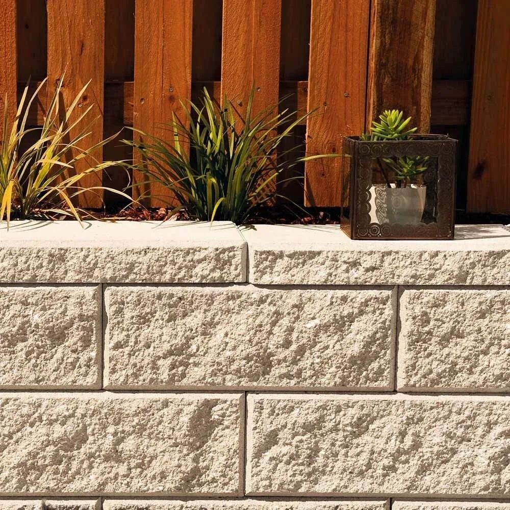 Stone Block Retaining Wall With Plants and Wooden Fence in Background — Hunter Valley Bricks & Pavers in Scone, NSW