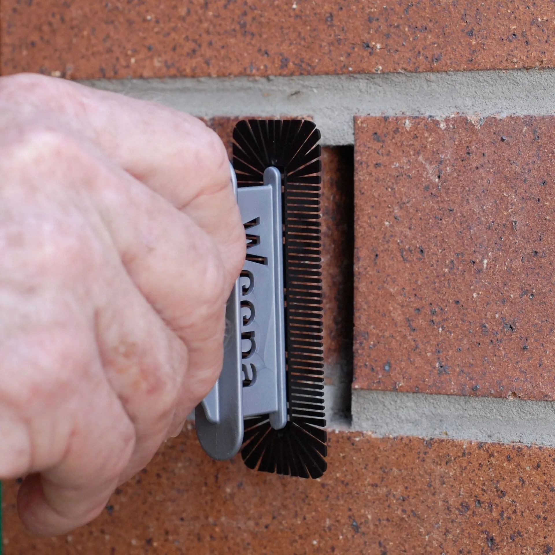 Hand Using a Mortar Joint Cleaning Tool on a Brick Wall, Cleaning the Mortar — Hunter Valley Bricks & Pavers in Scone, NSW