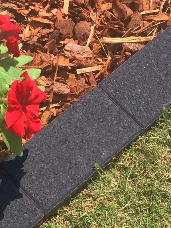 Black Paving Stones Border a Flower Bed With Red Flowers and Mulch — Hunter Valley Bricks & Pavers in Scone, NSW