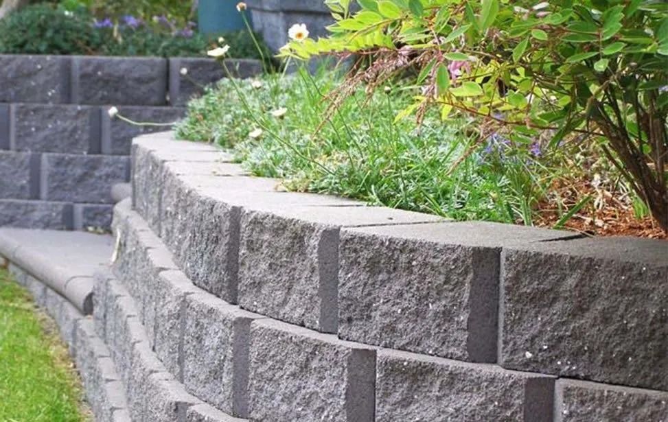 Gray Brick Retaining Wall With Plants and Steps in a Garden — Hunter Valley Bricks & Pavers in Scone, NSW