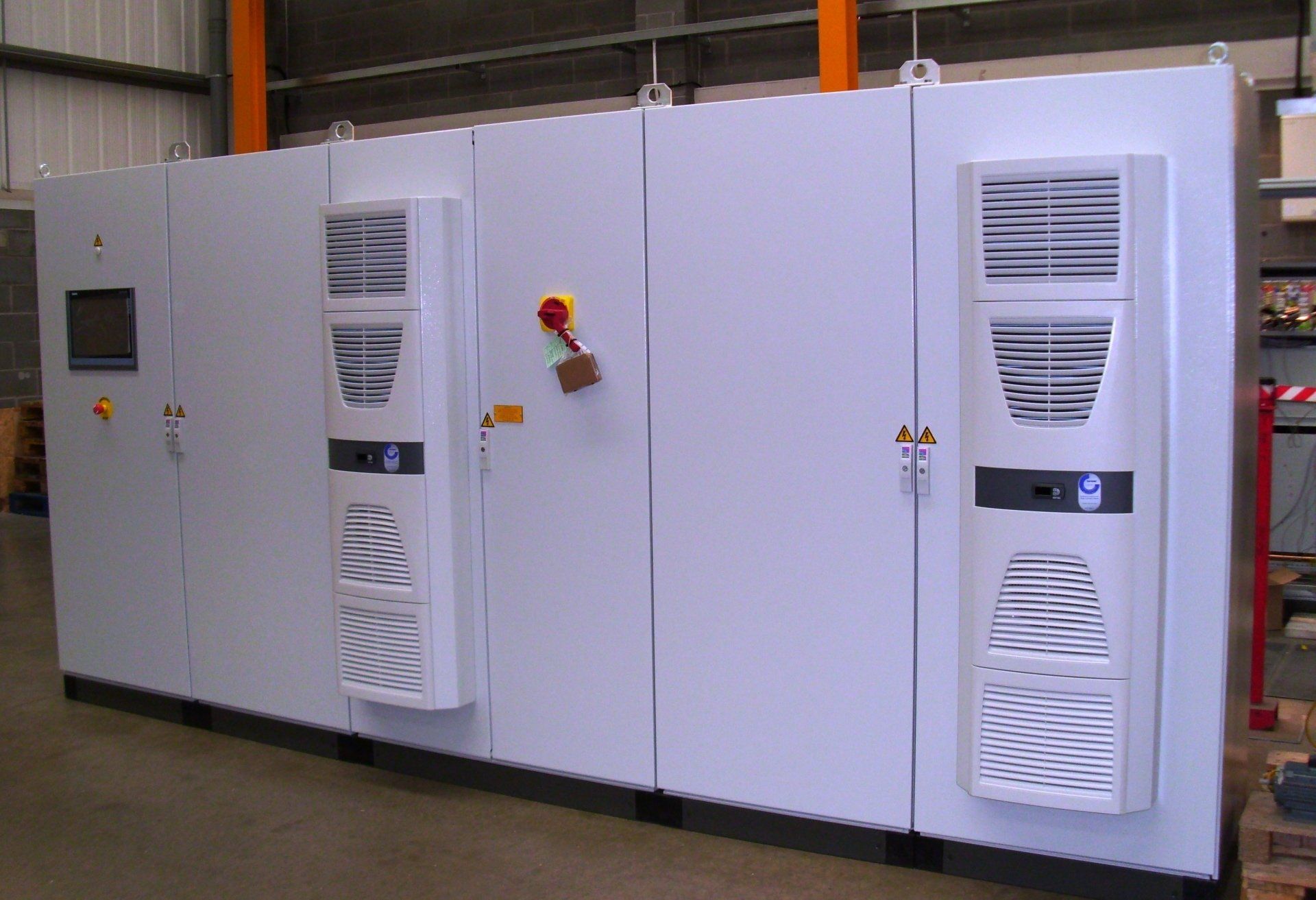 Front view of one of our multi bay panels with white panels with the far right panel containing one HMI panel and the middle panel containing a red emergency stop button