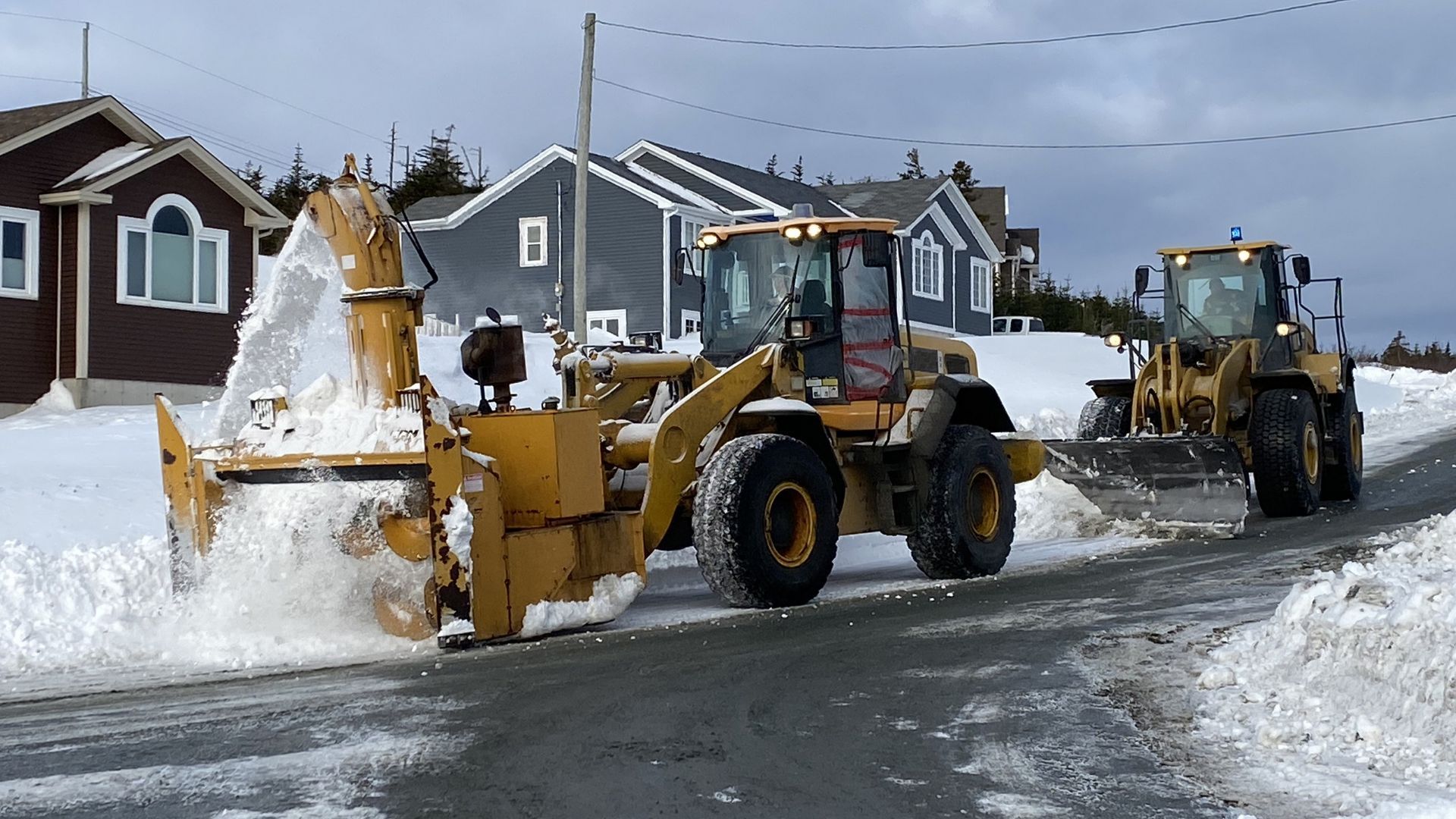 A snow blower is being pushed by a wheel loader