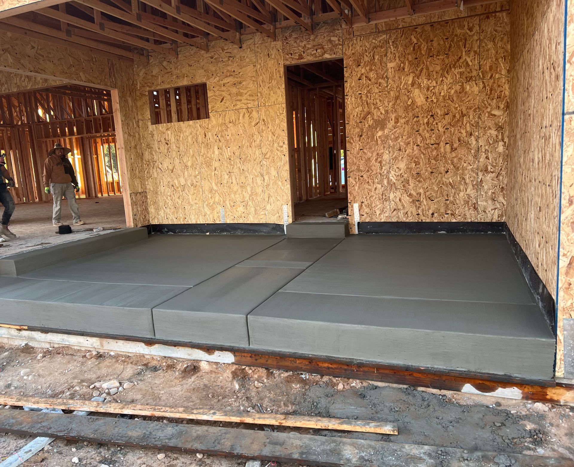 A concrete floor is being poured in a building under construction.