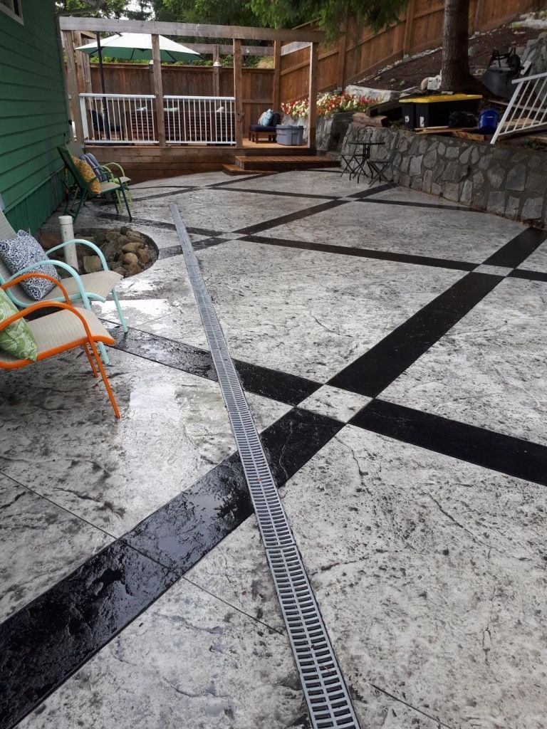 A hose is spraying water on a patio with a checkered pattern.