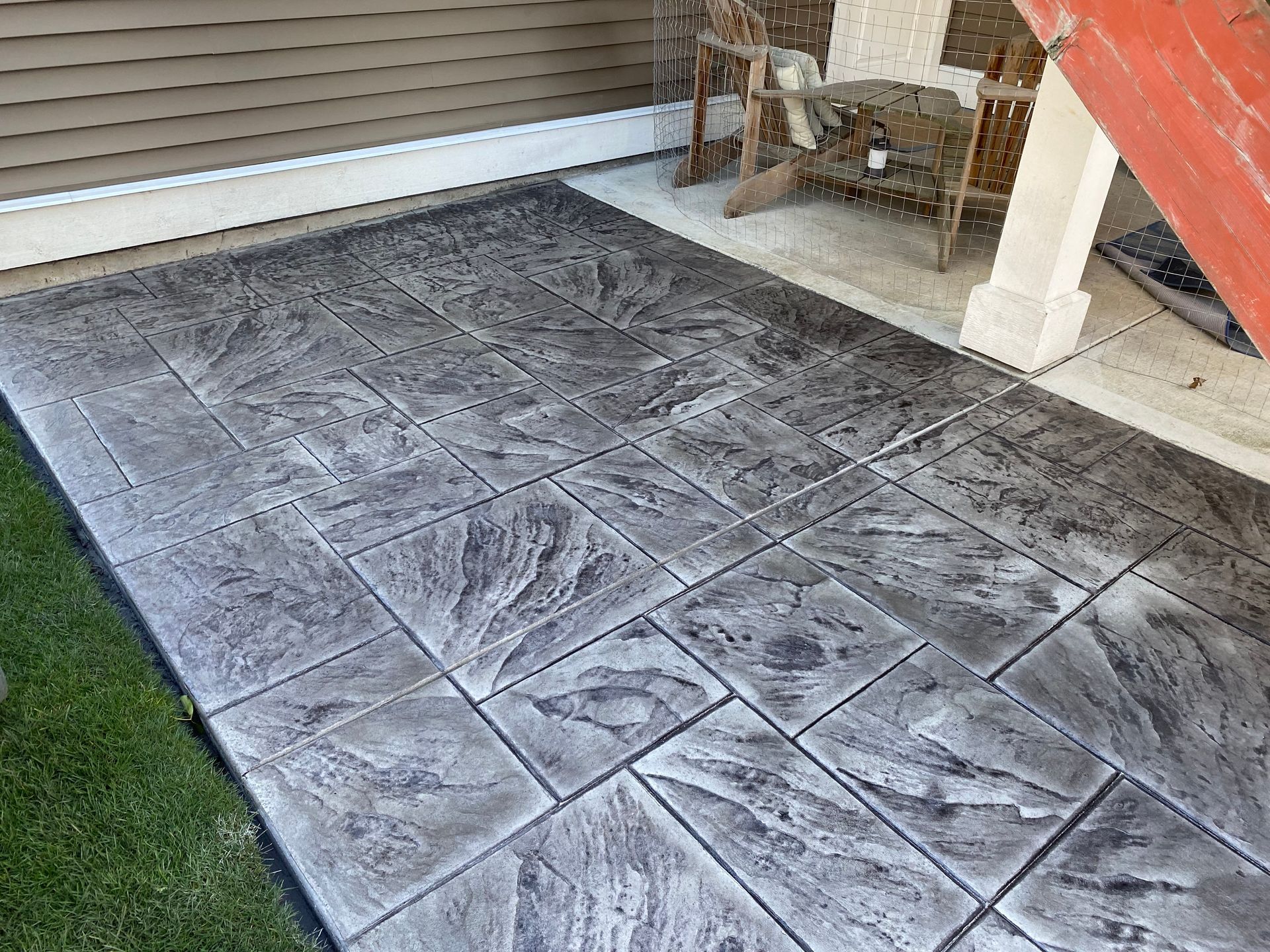 A patio with a concrete floor and a table and chairs on it.